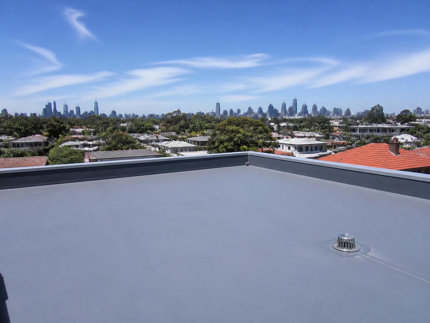 Flat rooftop with grey waterproofing membrane and drainage outlet